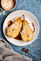 Tasty dessert of baked pears with caramel sauce, cheese cream and almond flakes