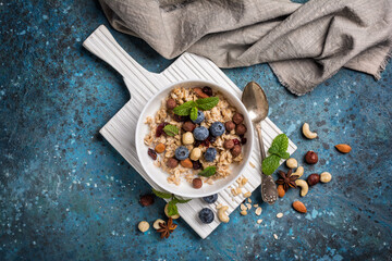 Healthy breakfast of oatmeal with milk, berry, nuts and mint