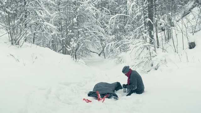 Winter, man tells wounded man on stretcher that it s not long to go. He allows victim to drink warm water from thermos. Concept of salvation, survival