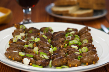 Chicken heart skewers cowered in scallions on a plate