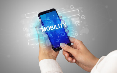 Female hand typing on smartphone with MOBILITY inscription, social media concept