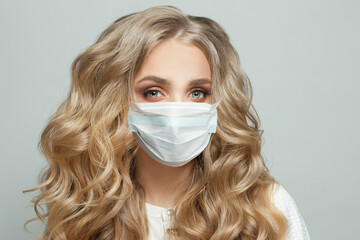 Healthy blonde woman in protective medical mask on white background