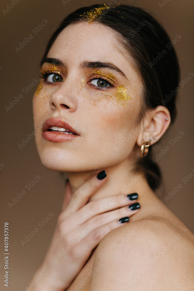 Sticker Close-up photo of curious young lady in golden jewerly. Studio portrait of glamorous brunette woman in earrings.