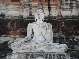 Ancient white old Buddha statue with pagoda wall background in Wat Yai Chai Mongkhon buddhist Temple in Phra Nakhon Si Ayutthaya Province, Thailand 