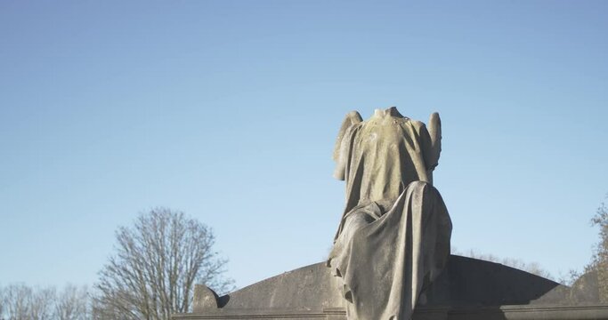 Old gothic headless angel headstone in a cemetary on a cold winter day