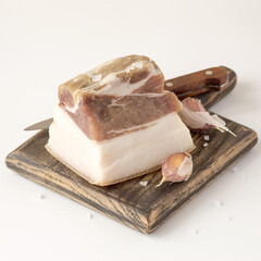 A piece of salted lard on a wooden cutting board. Selective focus.
