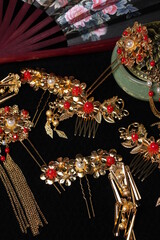 still life in Chinese style. traditional hairpins, incense burner and fan isolated on black background