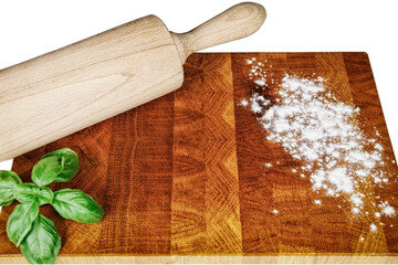 A kitchen wooden board dusted with a little flour, a kitchen roll and basil