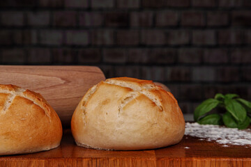 Fresh buns on a wooden board dusted with flour and a rolling pin in the background