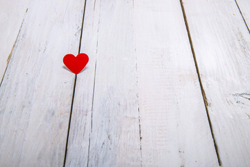 A little red paper heart on a white wooden background.To express love with a simple and deep thought.