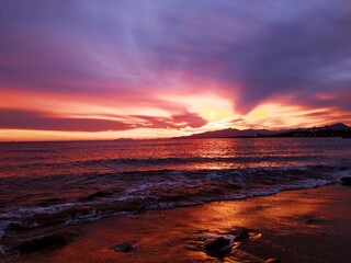 Obraz premium Atardecer teñido de rojo, mar colorido con la luz del cielo.