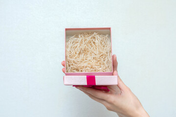 Hand shows a open gift with pink ribbon, woman's hands, close up