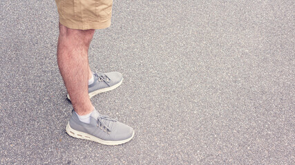 Person is about to take a step, asphalted street, feet in sneakers, close up, copy space, advertising, tonedб 16:9