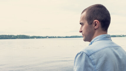 Attractive guy looking at the lake, back view, portrait, 16: 9