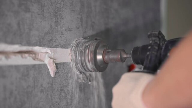 The guy is drilling the wall with a diamond bit