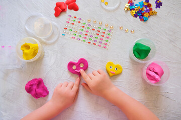 Child playing with colorful modeling clay with  beads and sequins and sculpting heart figure. Home Education game with clay.   Early development concept