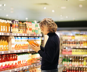 young man shopping in supermarket, reading product information.
