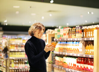 young man shopping in supermarket, reading product information.