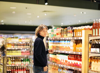 young man shopping in supermarket, reading product information.