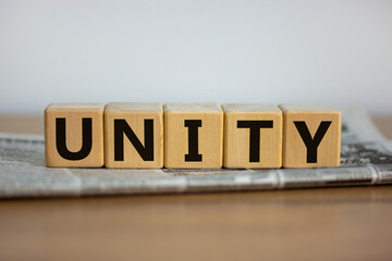 Time to unity symbol. Wooden cubes placed on a newspaper. The word 'unity'. Beautiful wooden table. White background. Business and unity concept. Copy space.