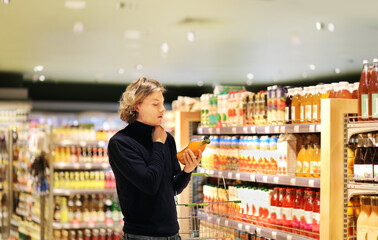 young man shopping in supermarket, reading product information.