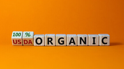 100 percent organic symbol. Fliped wooden cubes and changed words USDA organic to 100 percent organic. Beautiful orange background, copy space. Business, healthy lifestyle 100 percent organic concept.