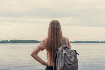 Woman on the background of the lake, forest and lake, woman with backpack, rear view, toned