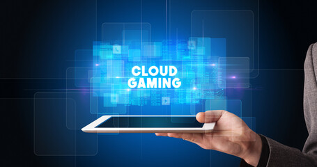 Young business person working on tablet and shows the inscription: CLOUD GAMING