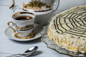 Cup of tea and esterhazy cake on a light background