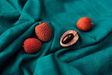 Aesthetic layout of  fresh organic Lychee (Litchi fruit) against  dark cyan cloth background.