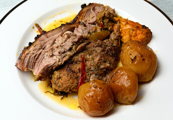 Portion of homemade roast pork with potatoes in white plate