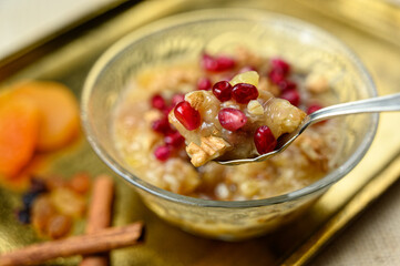 Ashure or Noah's pudding, the turkish dessert porridge in glass bowl on golden dish