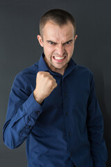 Evil businessman showing fists at camera, black background, vertical