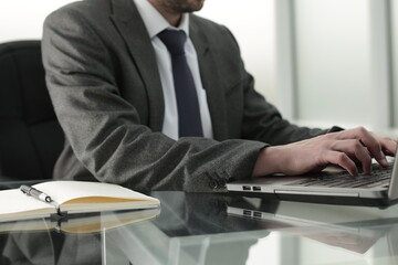 The director of the company works in the office, typing on a laptop keyboard