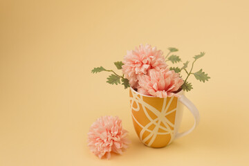 Minimal concept of a small bouqet of pink flowers and leaves in the mug. Vintage spring concept. Beige pastel background. Retro fashion aesthetic.