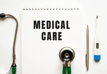 MEDICAL CARE text written in a notebook lying on a desk and a stethoscope.