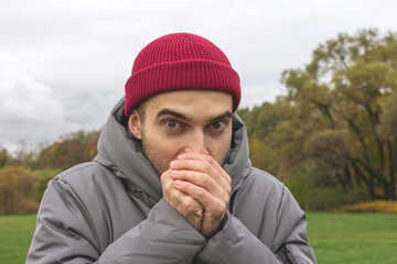 Person freezes on the street, a man is warmly dressed on an autumn seasonal day, portrait, close-up