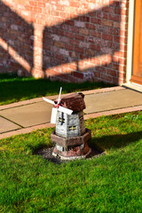 A small windmill on a green lawn.