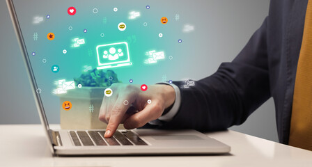 Hand surfing on the social media with laptop icons coming out from the screen, networking concept