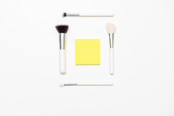 Makeup brushes and a sheet of paper on a white background, copying space, advertising, slogan, text, top view