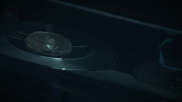 
Macro shots of a 1970s quarter-inch open-reel tape recorder in operation. Shallow depth of field with focus on the rotating spools. Suggestive of a wiretap or surveillance. 