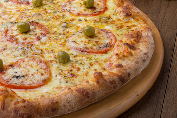 Close-Up Photograph of a Mozzarella Cheese Pizza with Sliced ​​Red Tomatoes on a Wooden Board. Food aligned to the left.