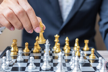 businessman hand moving gold Chess King figure and Checkmate enermy or opponent during chessboard competition. Strategy, Success, management, business planning, interruption and leadership concept