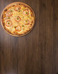 Tasty mozzarella cheese pizza with slices of red tomatoes on a wooden board. Vertical top shot with food aligned on the upper left side. Space for texts.