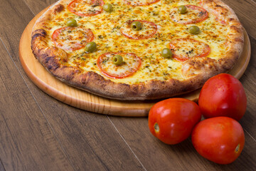 ricardo fernando franca junior pizza mussarela muçarela mucarelTasty mozzarella cheese pizza with slices of red tomatoes on a wooden board. Red rustic tomatoes. Gastronomic photography close.