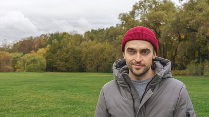 Man standing in a Park in autumn, a man with a thoughtful expression on the background of an autumn Park, portrait, 16: 9