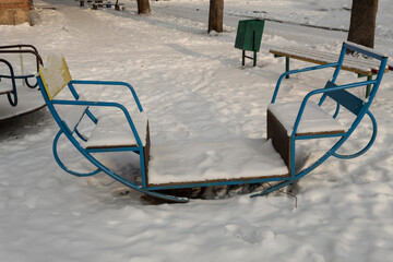 Children's swing on the playground in winter in the snow.