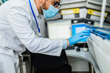 Scientist or technician with protective face masks working in modern laboratory. Coronavirus, Covid-19 concept.