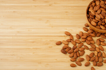 Organic almond nut raw peeled in bowl on wooden table, top view. Healthy snack or for vegetarians. 