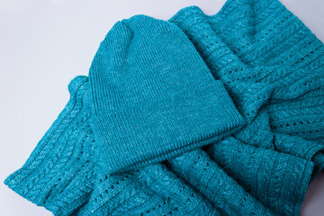 Hat and a scarf on a grey background. Warm set of clothes for autumn and winter. Turquoise color